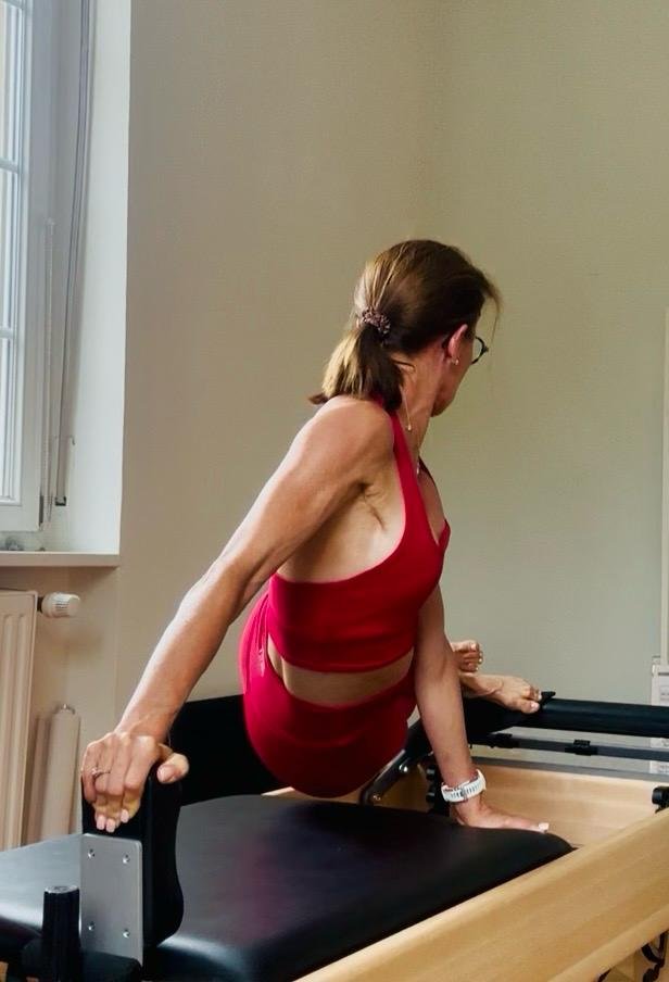 Armelle en appui sur le Reformer, face à la lumière de la fenêtre